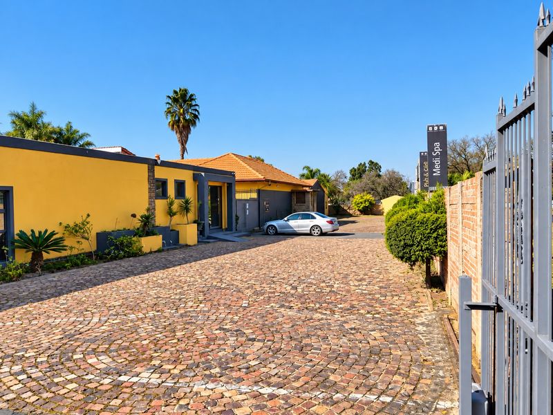 Front exterior view of a commercial property featuring a cobblestone driveway, secure metal gate, and prominent signage for a Medi-Spa facility.