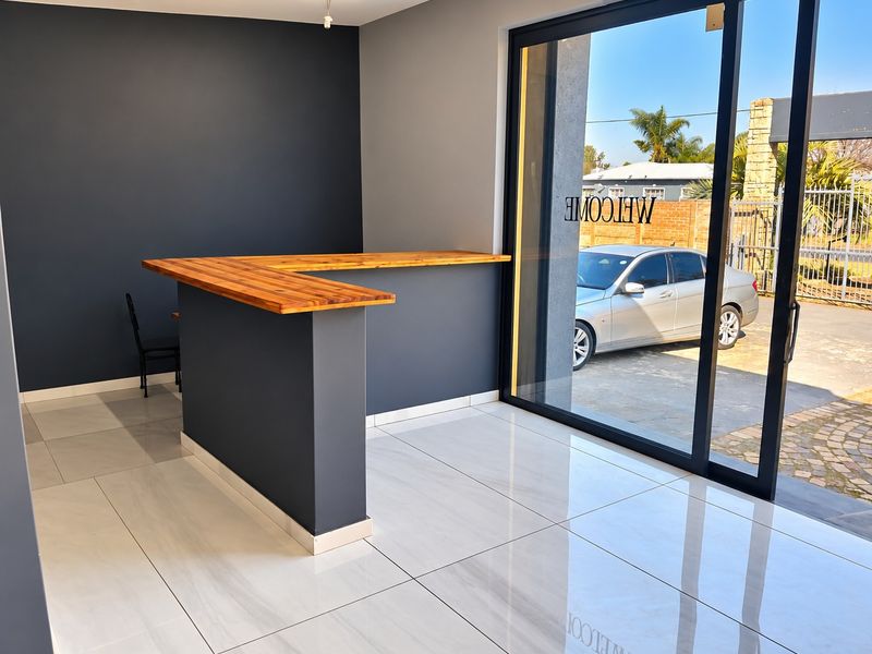 Modern commercial entry area featuring a sleek built-in reception counter, polished porcelain floor tiles, and large glass sliding doors providing natural light.