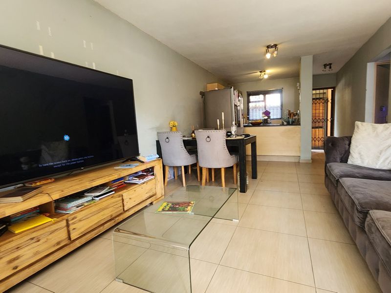 Open-plan living and dining area featuring tiled flooring and a breakfast bar connecting to the kitchen space.