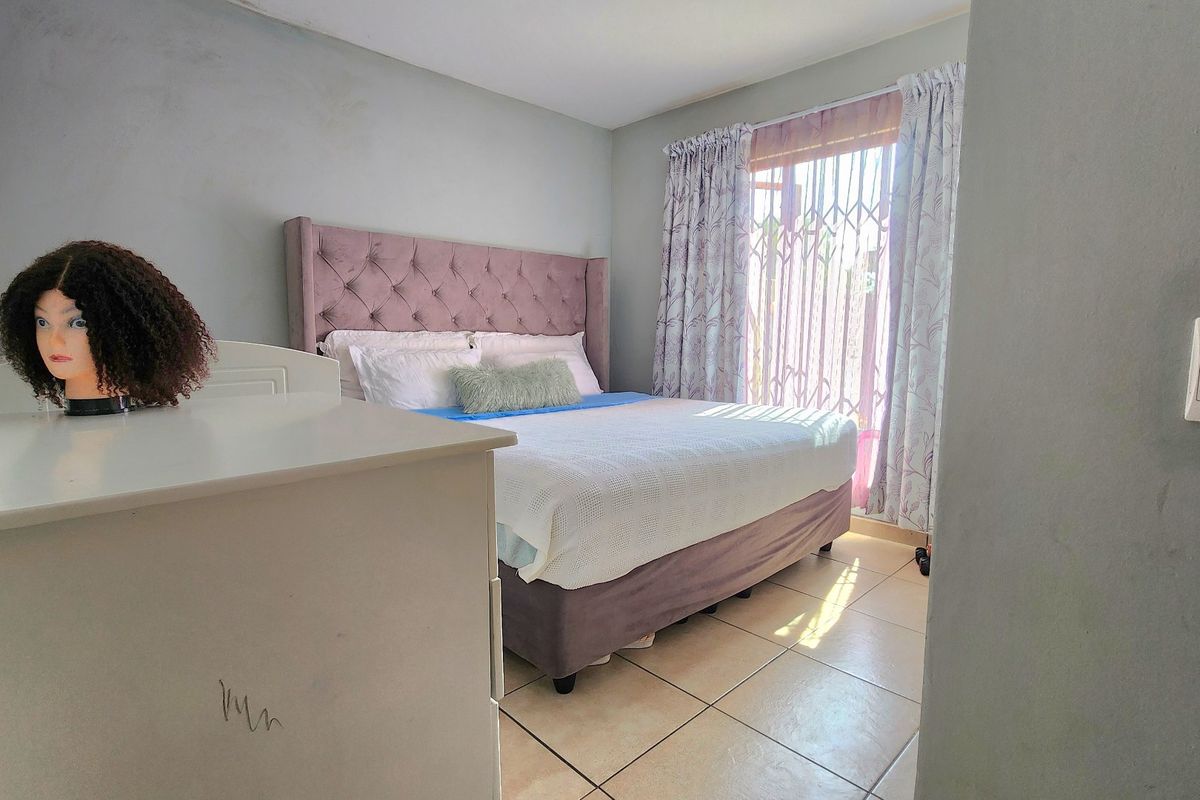 A bedroom featuring tiled flooring and a security gate over the window, providing a functional space with neutral wall finishes.