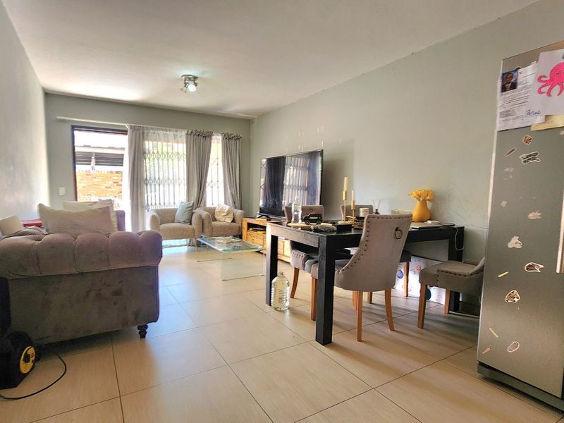 Open-plan living and dining area featuring neutral tiled flooring and a sliding glass door leading to an outdoor space.