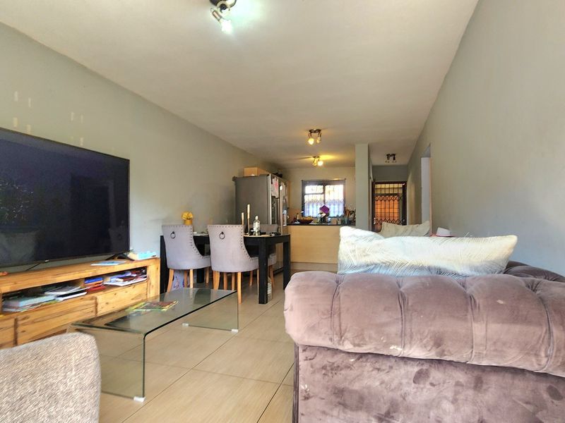 Open-plan living and dining area featuring tiled flooring and a connected kitchen space, providing a functional layout for daily living.