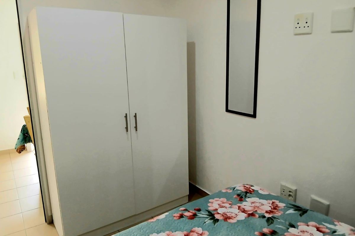 A bedroom featuring white walls, electrical outlets, and light switches, providing a functional space for rest.