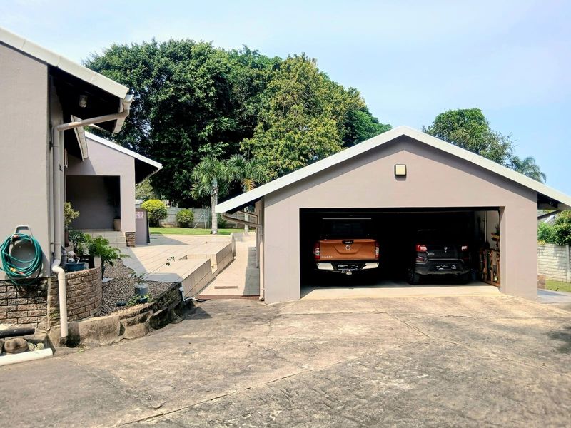 Exterior view of a detached garage with a concrete driveway and adjacent paved patio area.