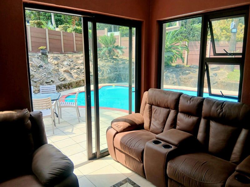 A living room featuring large sliding glass doors that provide direct access to an outdoor patio and swimming pool area.