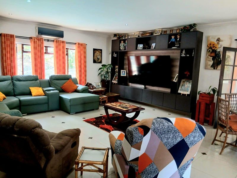 Spacious living room featuring a large built-in wall unit, tiled flooring, recessed lighting, and a wall-mounted air conditioning unit.