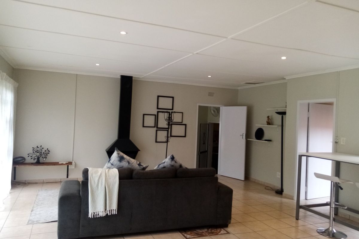 Spacious living room featuring tiled flooring, recessed ceiling lighting, and a prominent black fireplace, offering a neutral and functional living space.