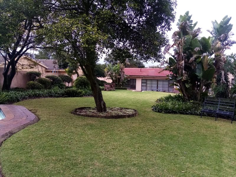 A well-maintained garden featuring a lush green lawn, mature trees, and landscaped beds, providing a peaceful outdoor space.