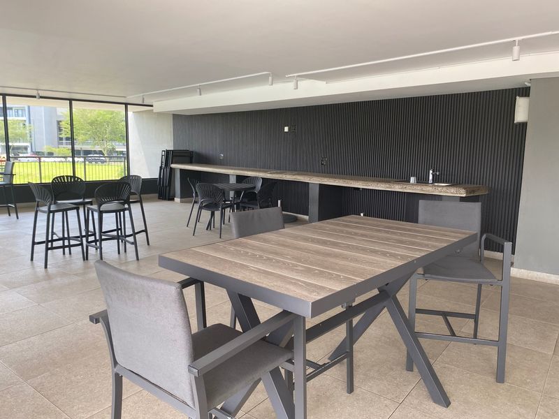 A spacious covered patio featuring a built-in bar counter, modern slatted wall paneling, and tiled flooring, ideal for outdoor entertaining.
