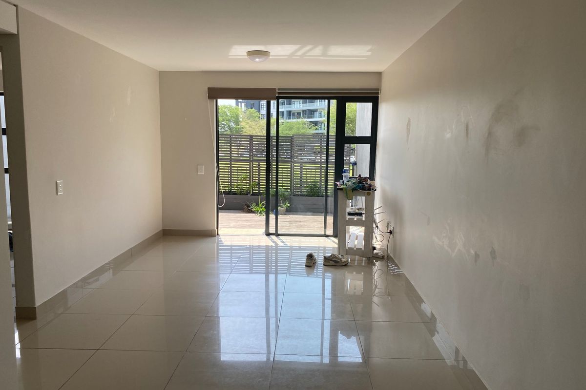 An empty living room featuring large format floor tiles and a sliding glass door leading to an outdoor patio area.
