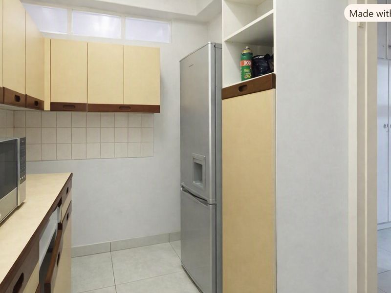 A functional kitchen featuring built-in cabinetry, tiled backsplash, and tiled flooring, offering a clean and practical layout for daily use.