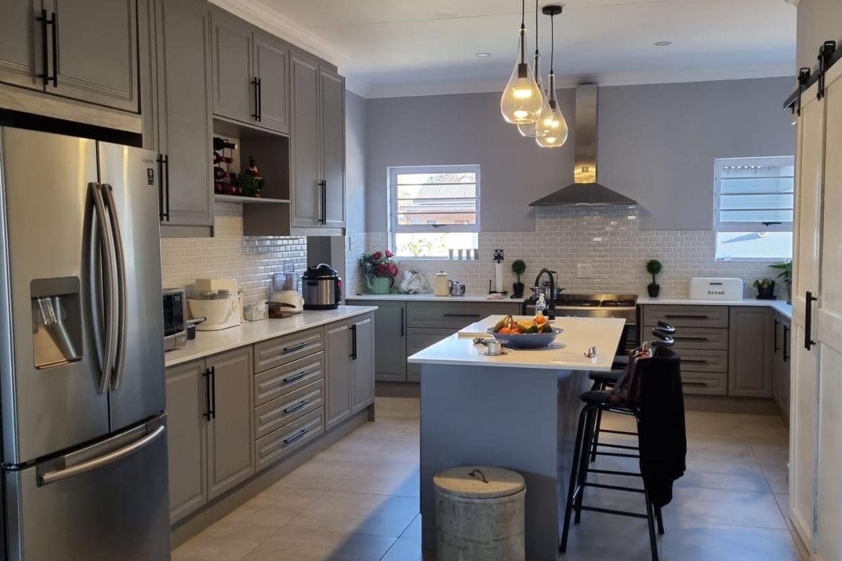 Modern kitchen featuring grey shaker cabinetry, quartz countertops, subway tile backsplash, a central island, and high-quality stainless steel appliances.