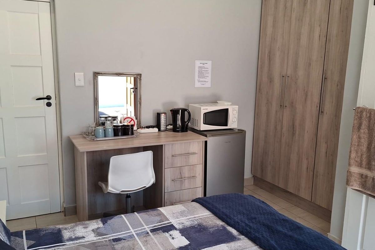 A well-maintained bedroom featuring built-in wooden wardrobes, tiled flooring, and neutral wall finishes.