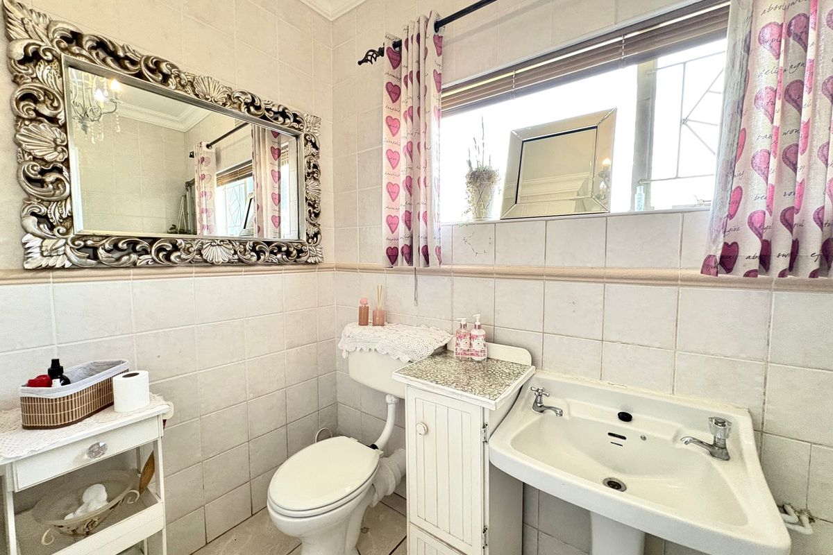 A functional bathroom featuring tiled walls and flooring, a pedestal basin, and a built-in vanity cabinet.