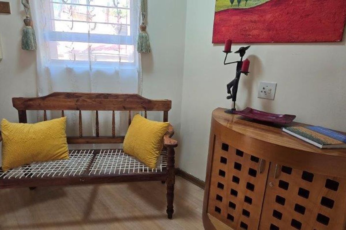 A small living area featuring laminate flooring and a window with security bars, providing a functional space for seating.