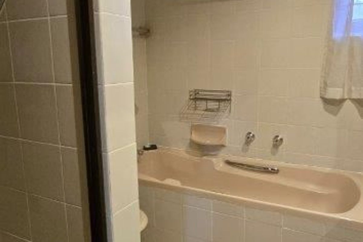 A dated bathroom featuring a built-in bathtub, separate shower enclosure, and tiled finishes throughout, offering potential for a modern renovation.