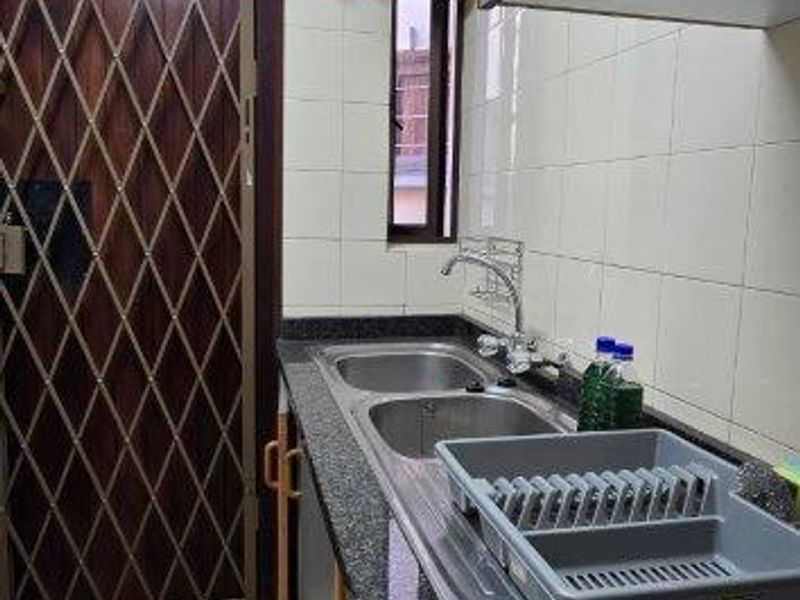 A functional scullery area featuring granite countertops, a double stainless steel sink, built-in cabinetry, and a secure metal gate.