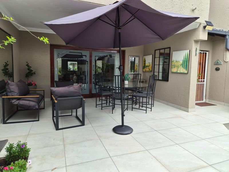 A covered patio area featuring large format floor tiles, sliding glass doors providing access to the interior, and a secure entrance gate.