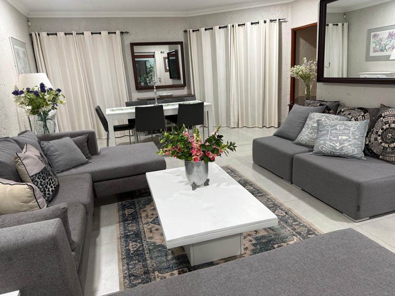Spacious open-plan living and dining area featuring neutral tiled flooring and classic coved cornicing, creating a comfortable and cohesive living space.