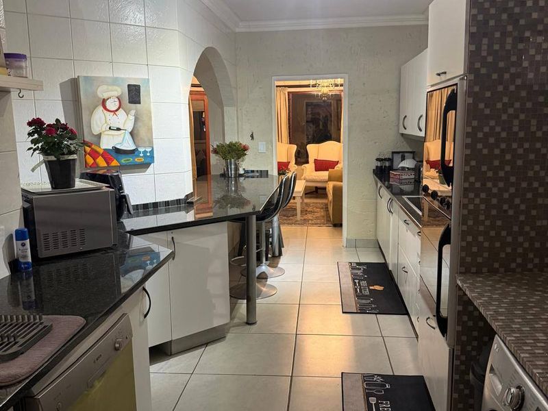 A functional kitchen featuring granite countertops, built-in cabinetry, an integrated oven, and a breakfast bar, leading through an archway to the living area.