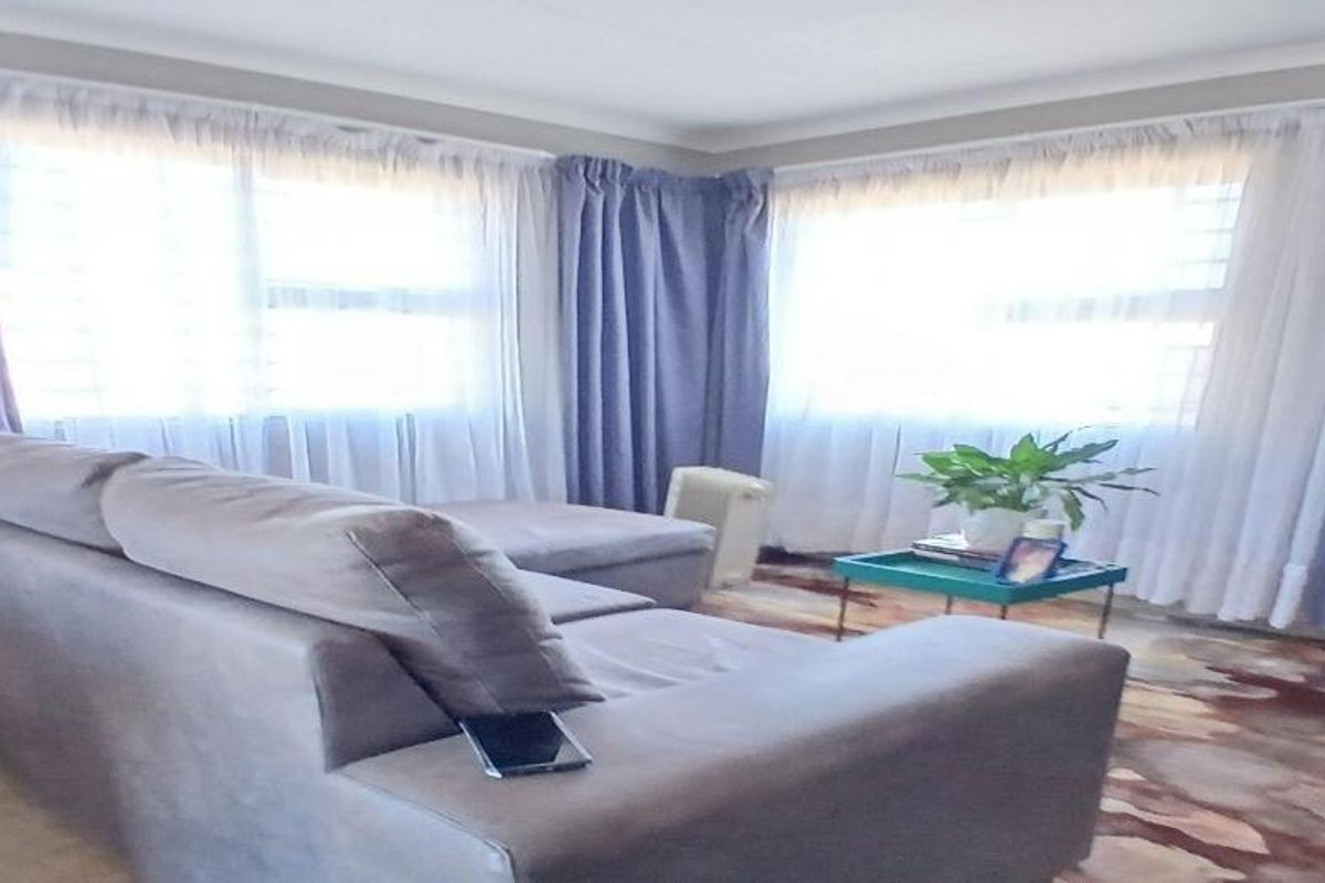 A living room featuring large windows with security bars and decorative cornicing, providing a bright and functional space.