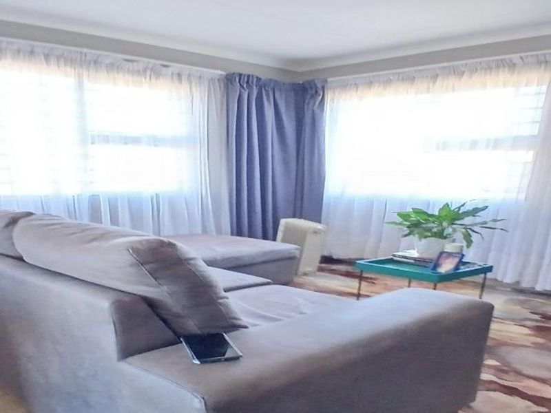 A living room featuring large windows with security bars and decorative cornicing, providing a bright and functional space.