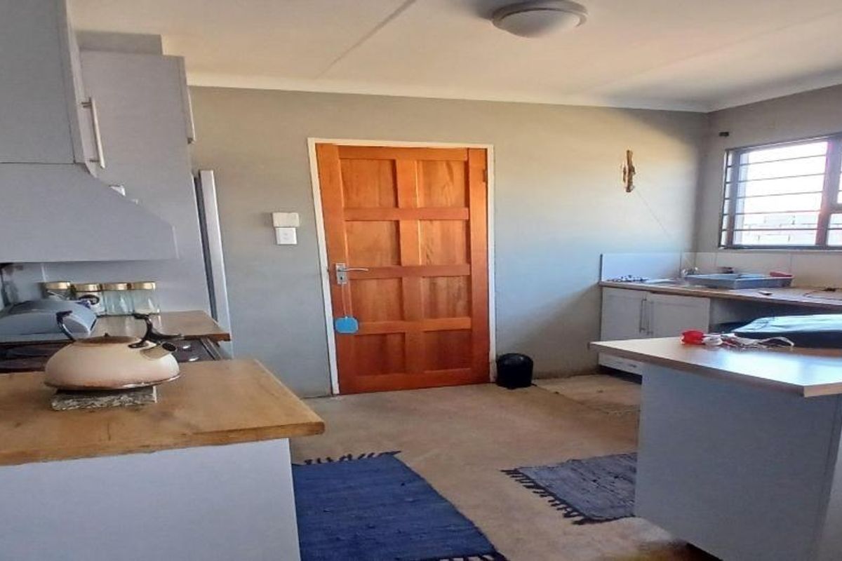 A functional kitchen featuring built-in cabinetry, wooden countertops, and a classic wooden door, offering a practical layout with natural light.
