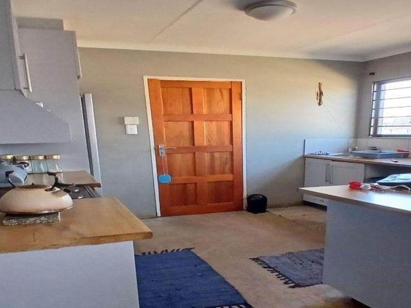 A functional kitchen featuring built-in cabinetry, wooden countertops, and a classic wooden door, offering a practical layout with natural light.
