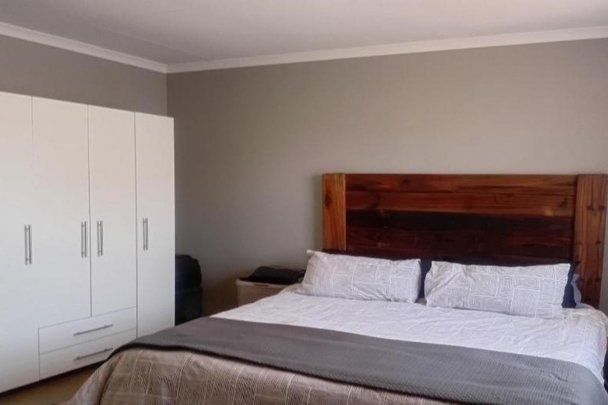 A well-maintained bedroom featuring neutral wall tones, coving, and a large built-in wardrobe providing ample storage space.