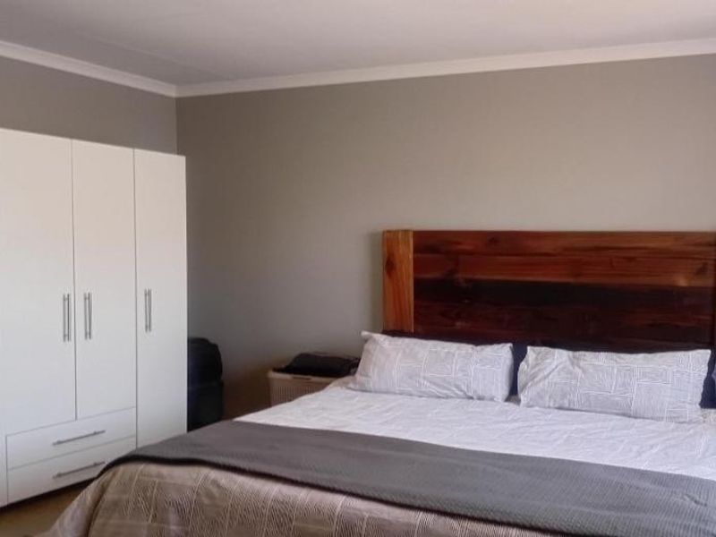 A well-maintained bedroom featuring neutral wall tones, coving, and a large built-in wardrobe providing ample storage space.