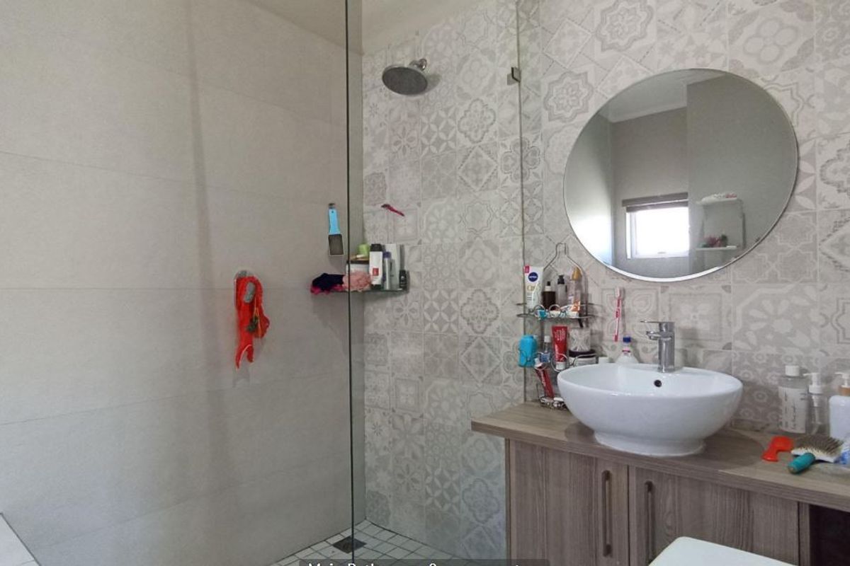 Modern bathroom featuring a walk-in shower with a glass screen, rain shower head, and a vanity unit with a vessel sink.