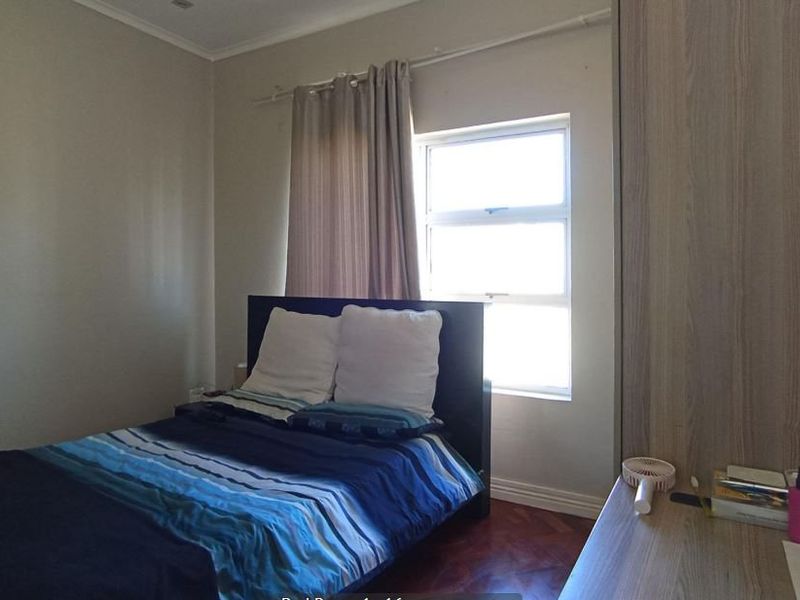 A bedroom featuring parquet flooring and a built-in wardrobe, providing a functional space with natural light from the window.