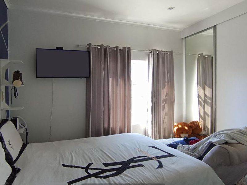 A well-lit bedroom featuring built-in sliding door wardrobes with mirrored panels and recessed ceiling lighting.