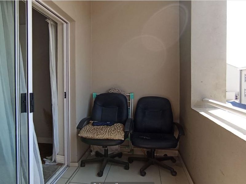 A covered balcony featuring tiled flooring and a metal balustrade, accessible via a sliding glass door.
