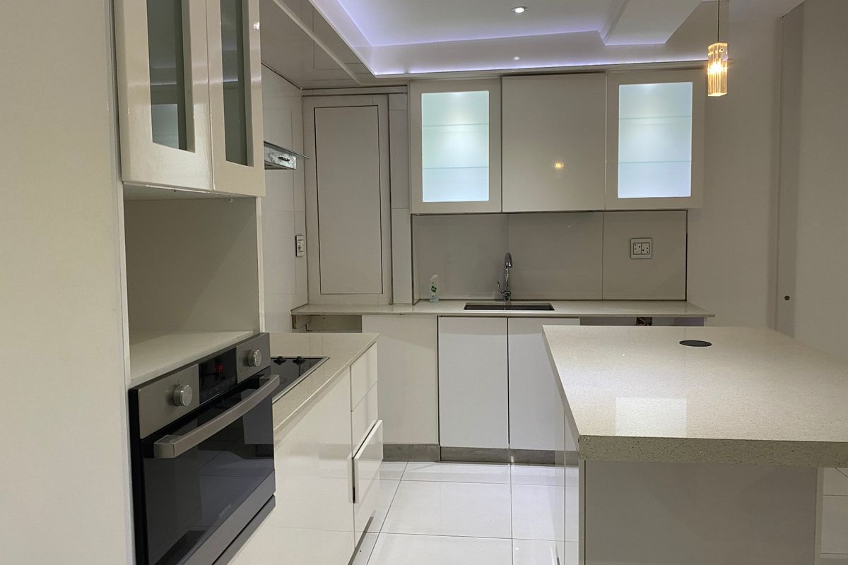 Modern kitchen featuring high-gloss cabinetry, quartz countertops, a central island, built-in oven, electric hob, and integrated lighting.