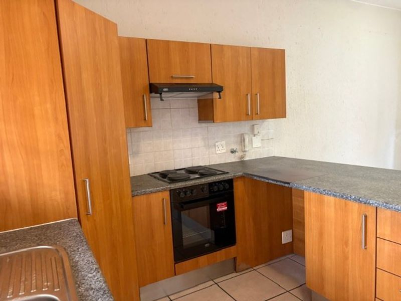 A functional kitchen featuring laminate cabinetry, granite countertops, a built-in oven with hob, and a tiled backsplash.