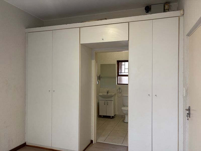 A bedroom featuring built-in cupboards with direct access to an en-suite bathroom, offering a functional layout ready for modernization.