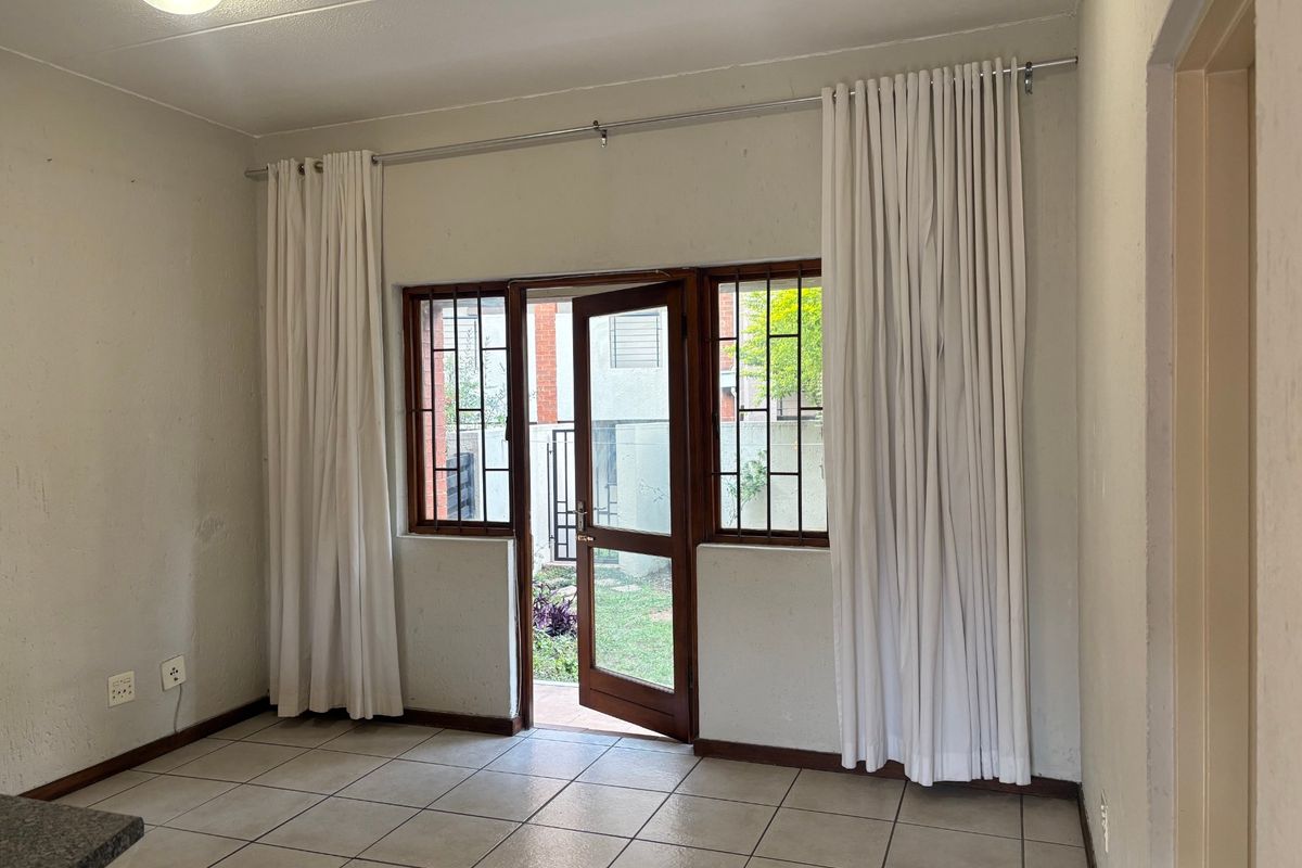 An empty living area featuring tiled flooring, a security gate, and direct access to an outdoor space.
