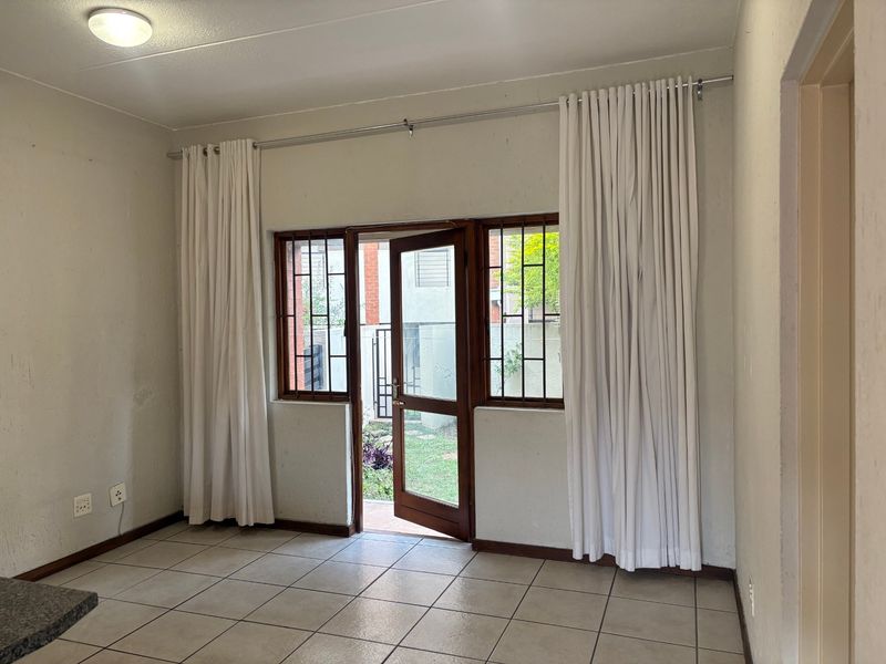 An empty living area featuring tiled flooring, a security gate, and direct access to an outdoor space.