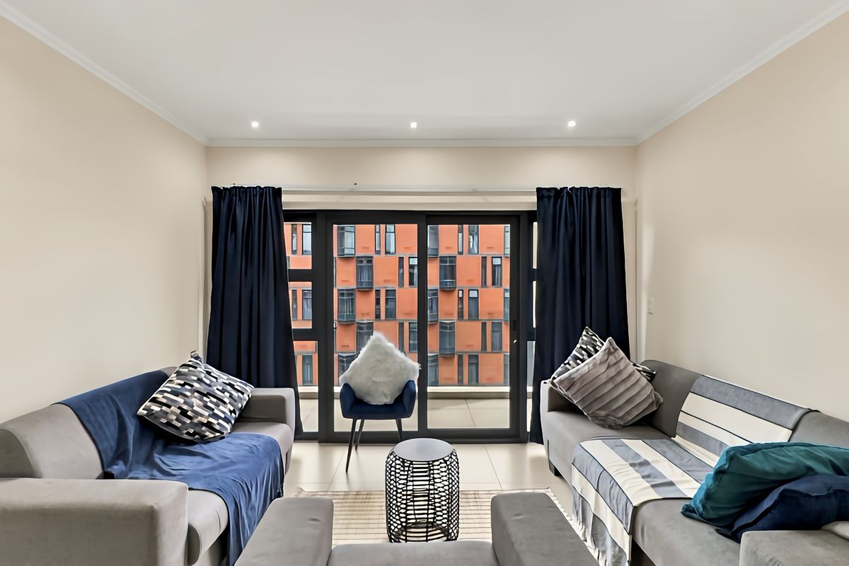 A well-lit living room featuring large sliding glass doors that provide access to a balcony and offer an urban view.