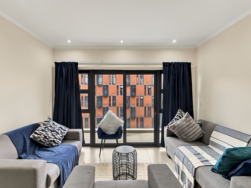 A well-lit living room featuring large sliding glass doors that provide access to a balcony and offer an urban view.