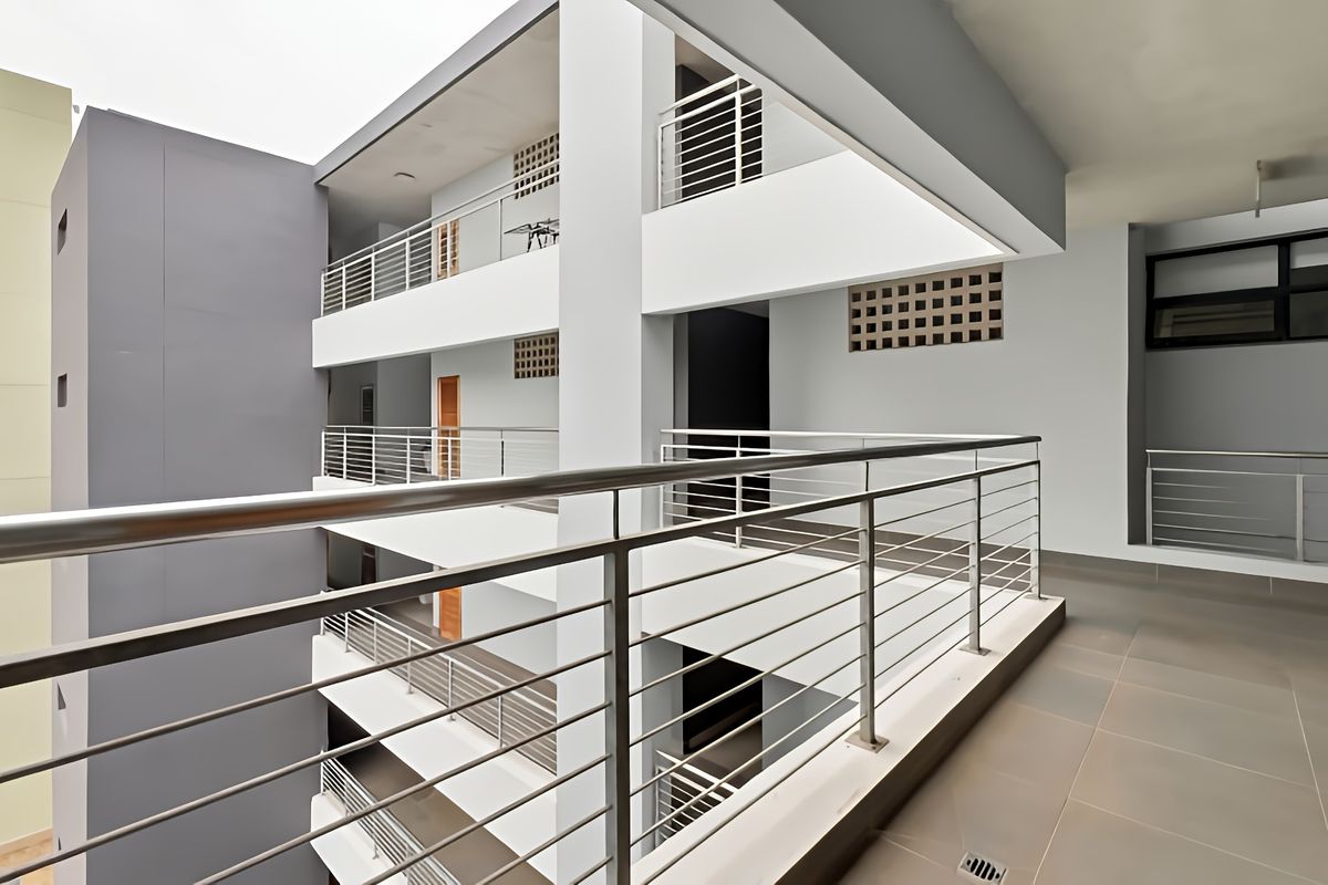 A modern apartment building exterior featuring multi-level walkways with stainless steel balustrades and clean, contemporary architectural finishes.