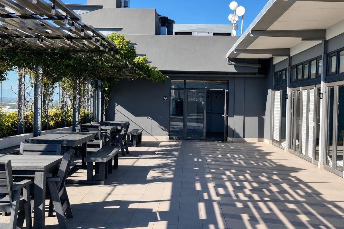 A spacious outdoor patio area featuring a pergola, tiled flooring, and glass sliding doors, providing a well-maintained space for outdoor relaxation.