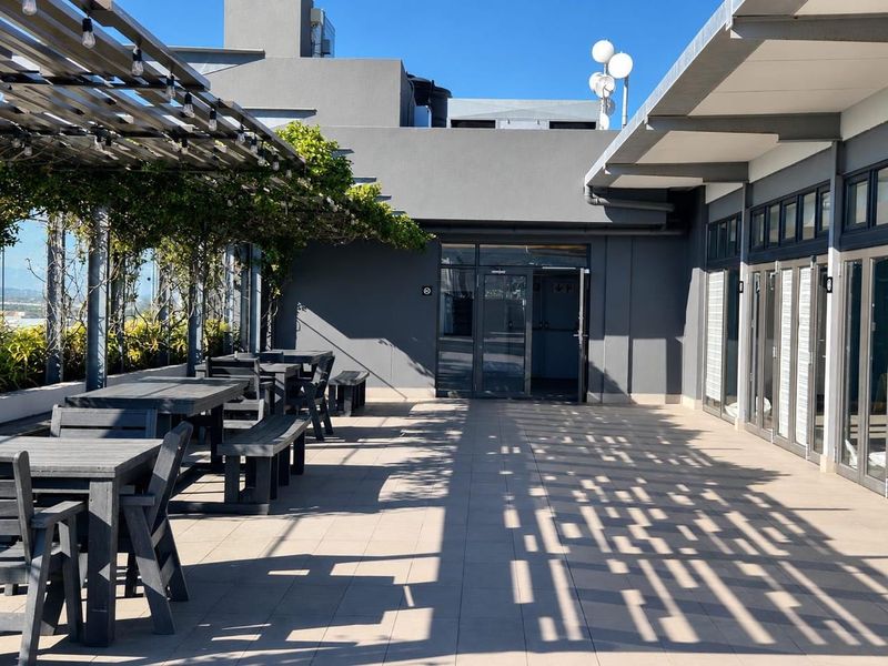 A spacious outdoor patio area featuring a pergola, tiled flooring, and glass sliding doors, providing a well-maintained space for outdoor relaxation.