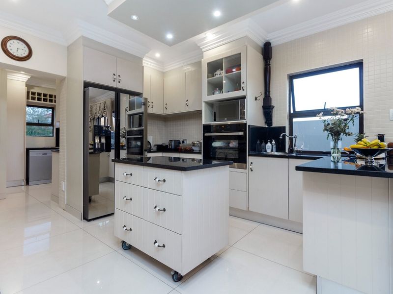 Modern kitchen featuring light-toned cabinetry, granite countertops, built-in appliances, and polished tiled flooring with a central mobile island.
