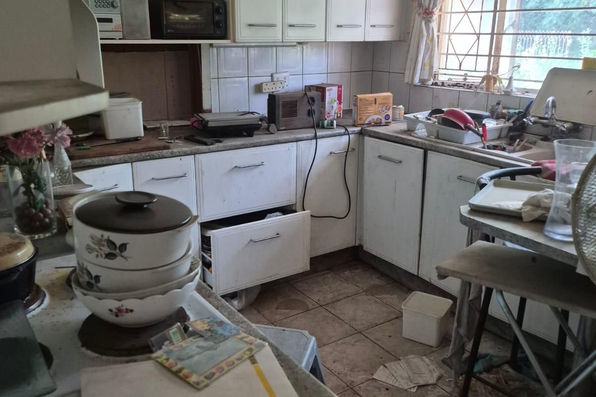 A dated kitchen featuring built-in cabinetry, tiled backsplash, and tiled flooring, requiring significant renovation and modernization to improve functionality and aesthetic appeal.