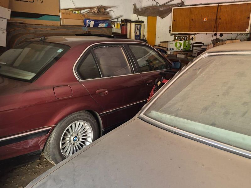 A cluttered garage space featuring wall-mounted storage cabinetry and basic ceiling lighting, showing signs of significant wear and surface deterioration.