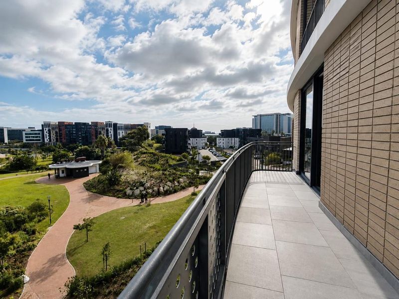A modern balcony with tiled flooring and a metal balustrade, offering expansive views over the surrounding landscaped estate and neighborhood.