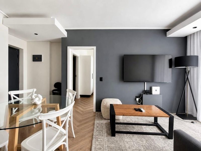 A modern living area featuring dark grey accent walls, herringbone timber flooring, and recessed ceiling lighting, creating a contemporary and well-maintained space.
