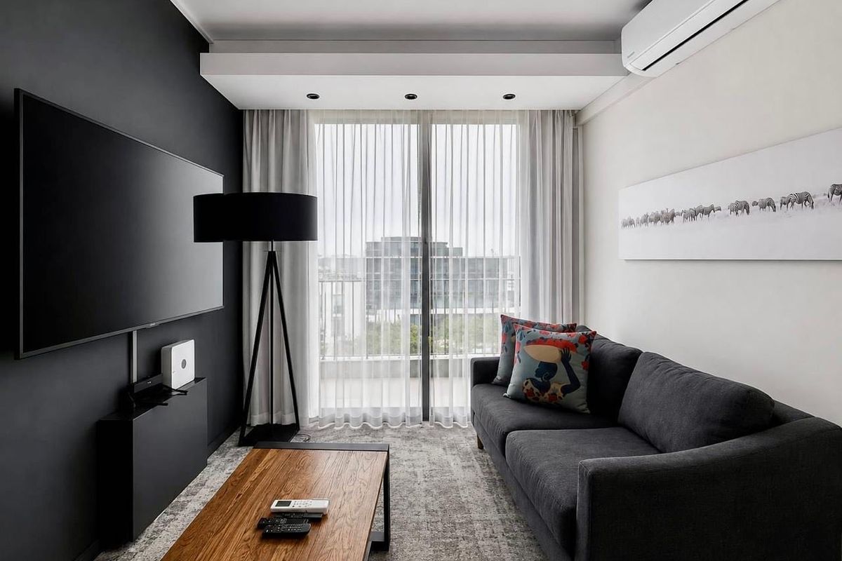 Modern living room featuring dark accent wall, recessed ceiling lighting, wall-mounted air conditioning, and sliding glass doors leading to a balcony.